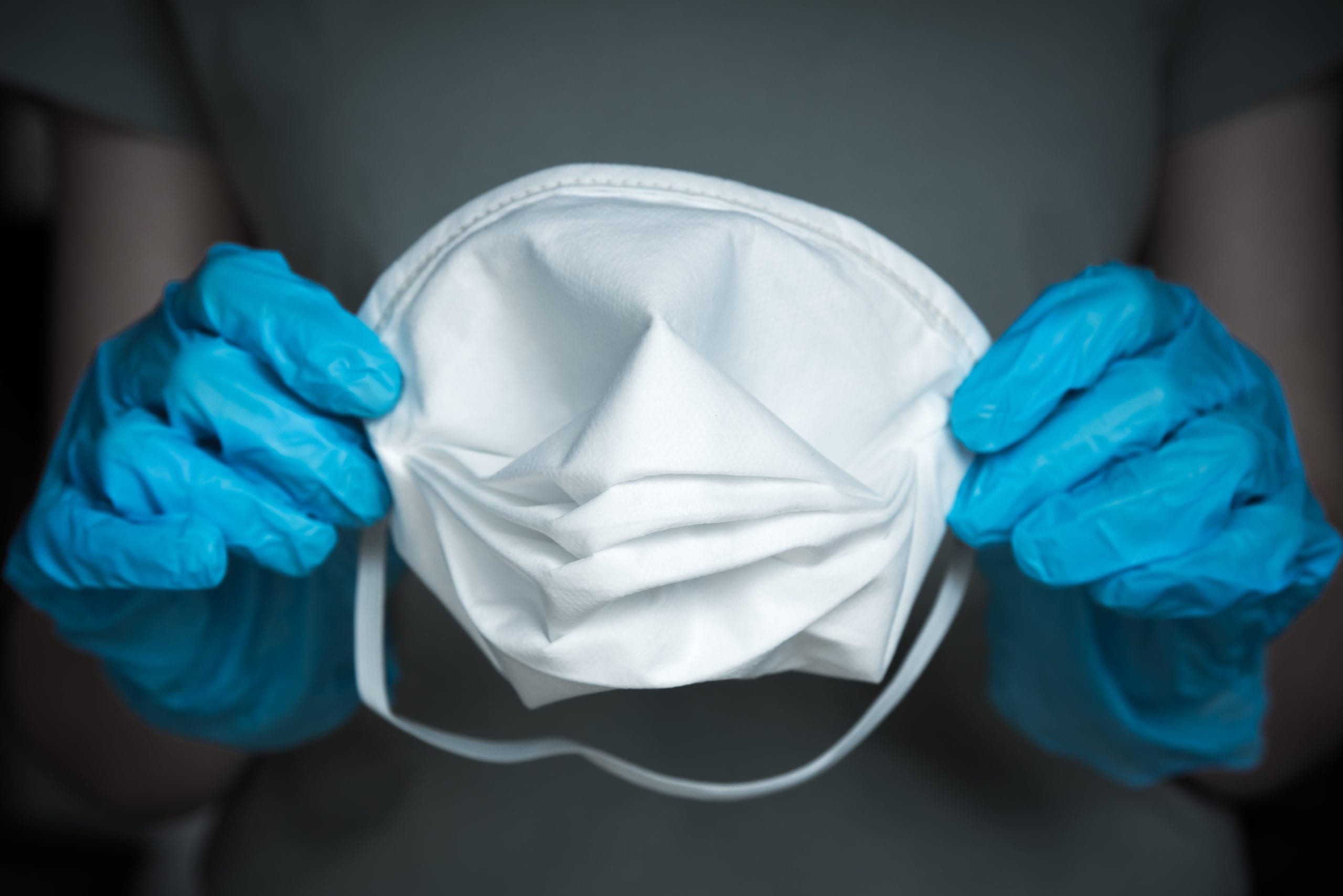 Close-up of gloved hands holding N95 medical face mask Close-up of gloved hands holding N95 medical face mask